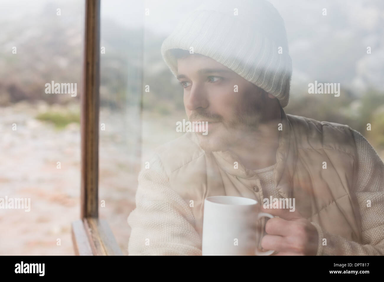 Thoughtful man with cup looking out through window Stock Photo