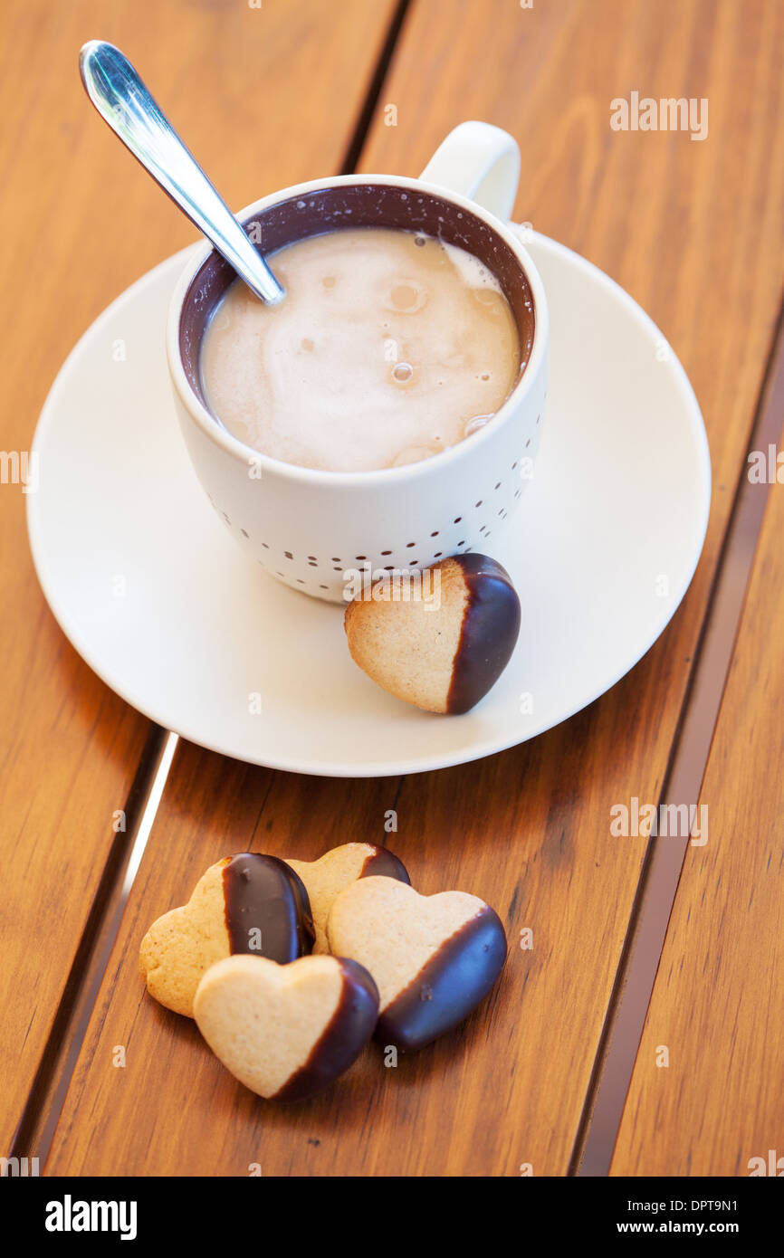 Cup of coffee served with chocolatedipped heart shaped biscuits Stock