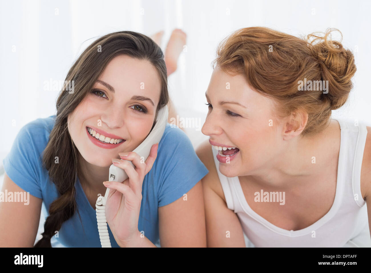 Woman with cheerful friend using phone in bed Stock Photo - Alamy