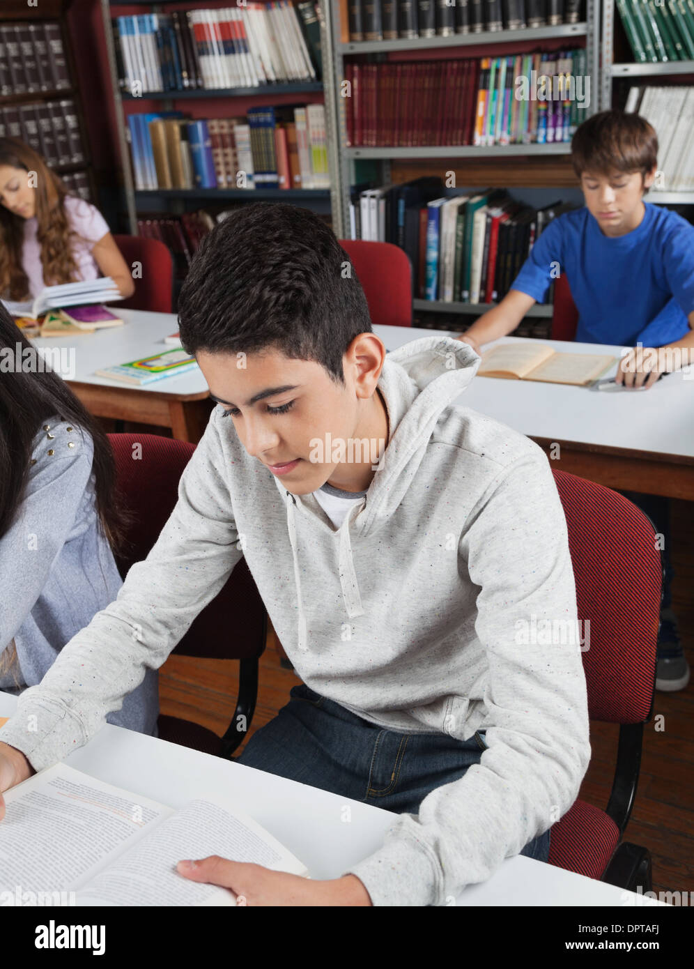 Male Student Reading Book In Library Stock Photo