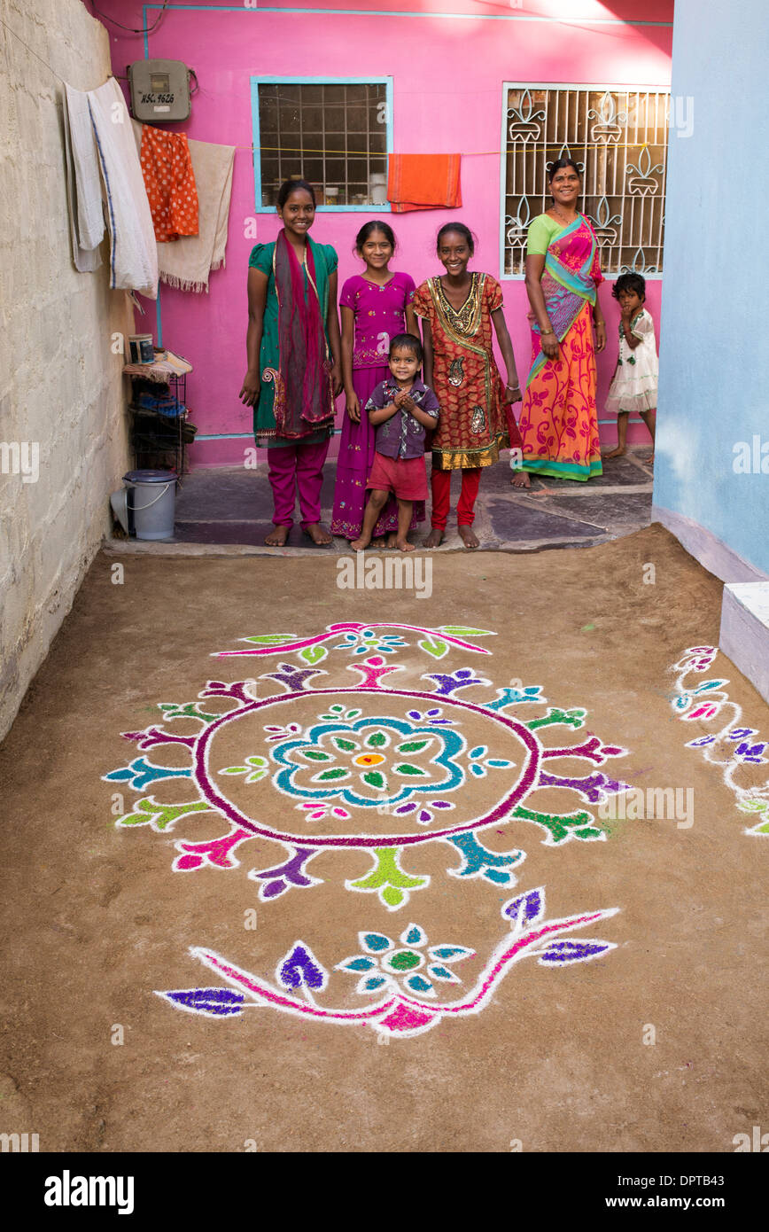 Indian girls standing next to a Rangoli festival coloured powder designs at Sankranti in a rural village. Andhra Pradesh, India Stock Photo