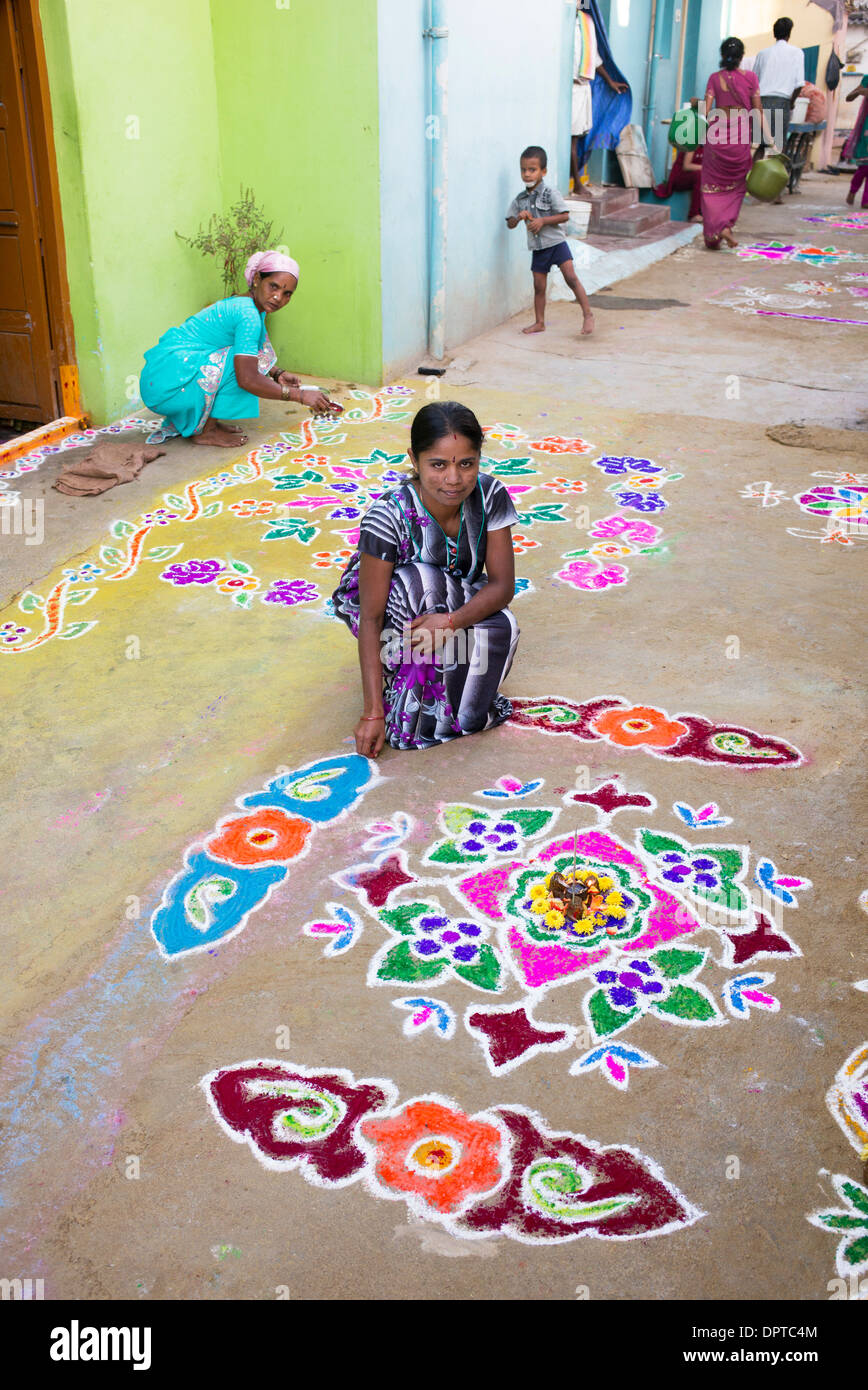 Indian woman making Rangoli festival coloured powder designs at Sankranti in a village street. Andhra Pradesh, India Stock Photo
