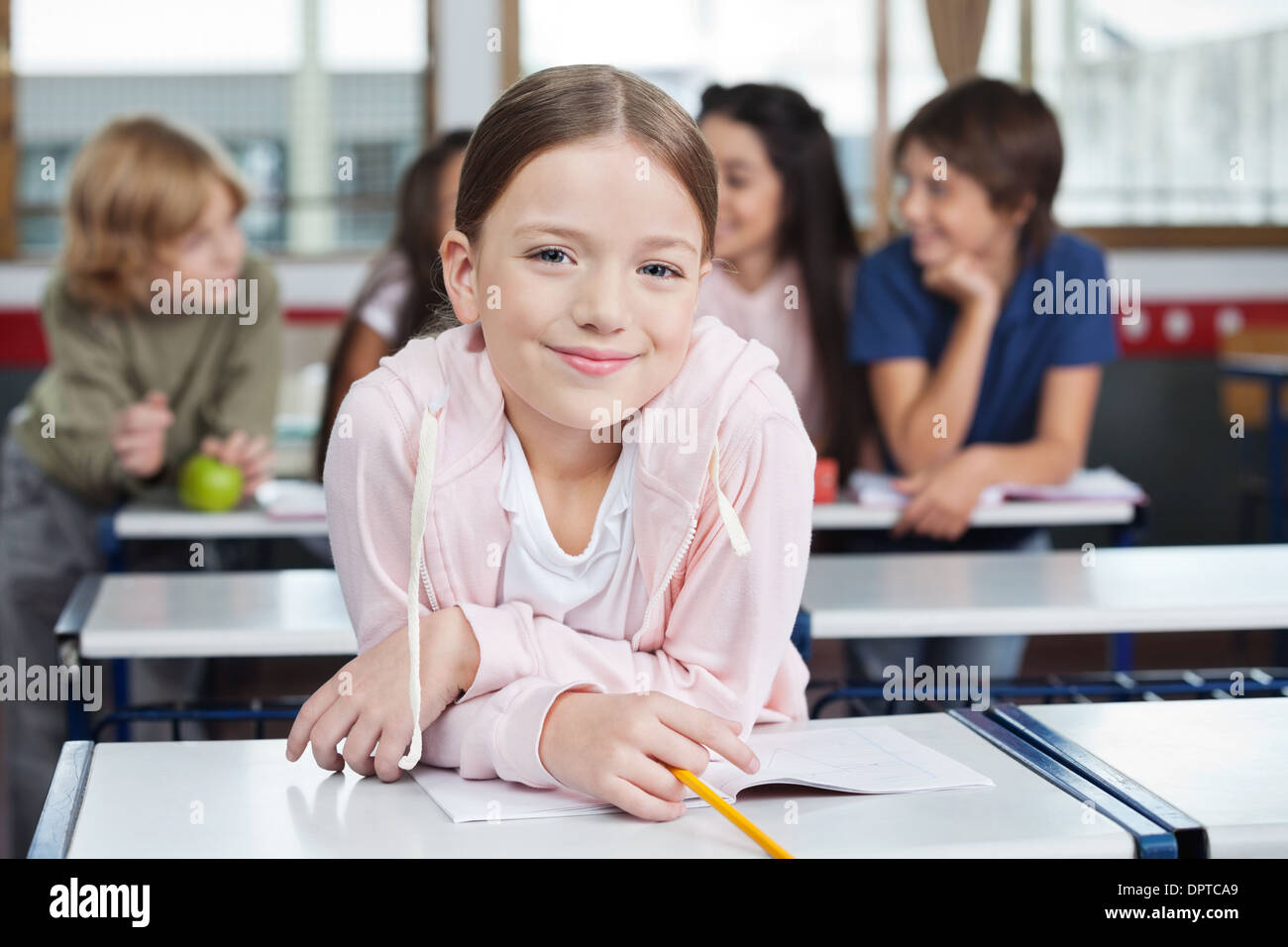 Schoolgirl Smiling While Leaning On Desk Stock Photo - Alamy