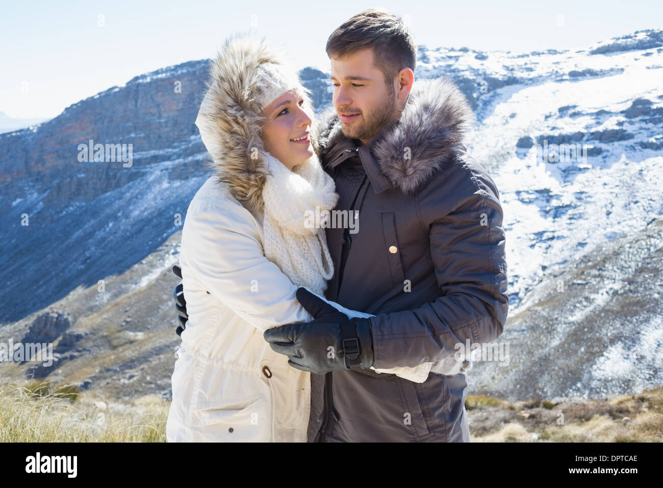 Loving couple in jackets against snowed mountain range Stock Photo