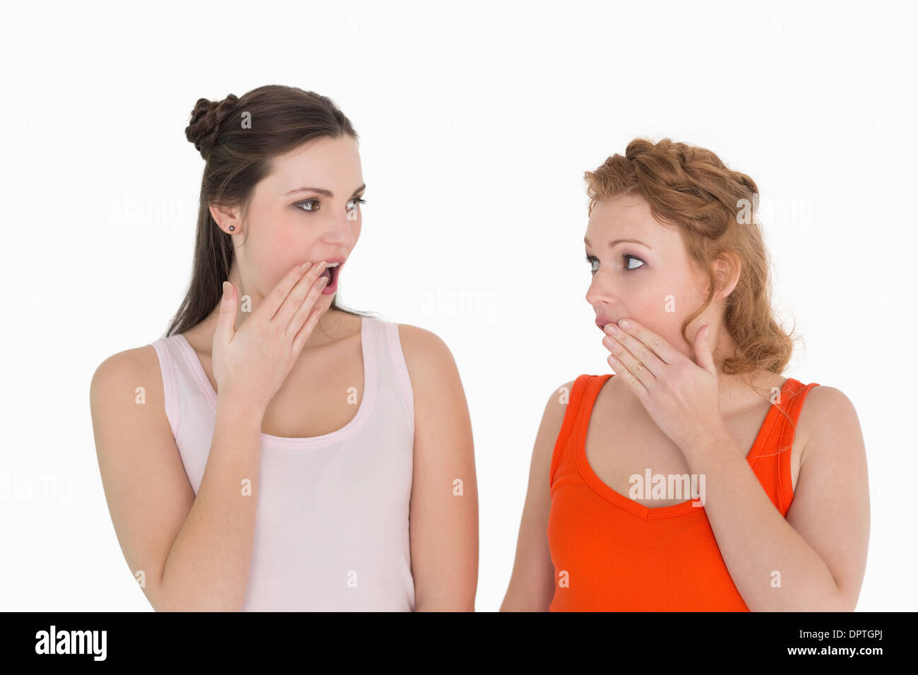 Two young shocked female friends with hand over mouth Stock Photo
