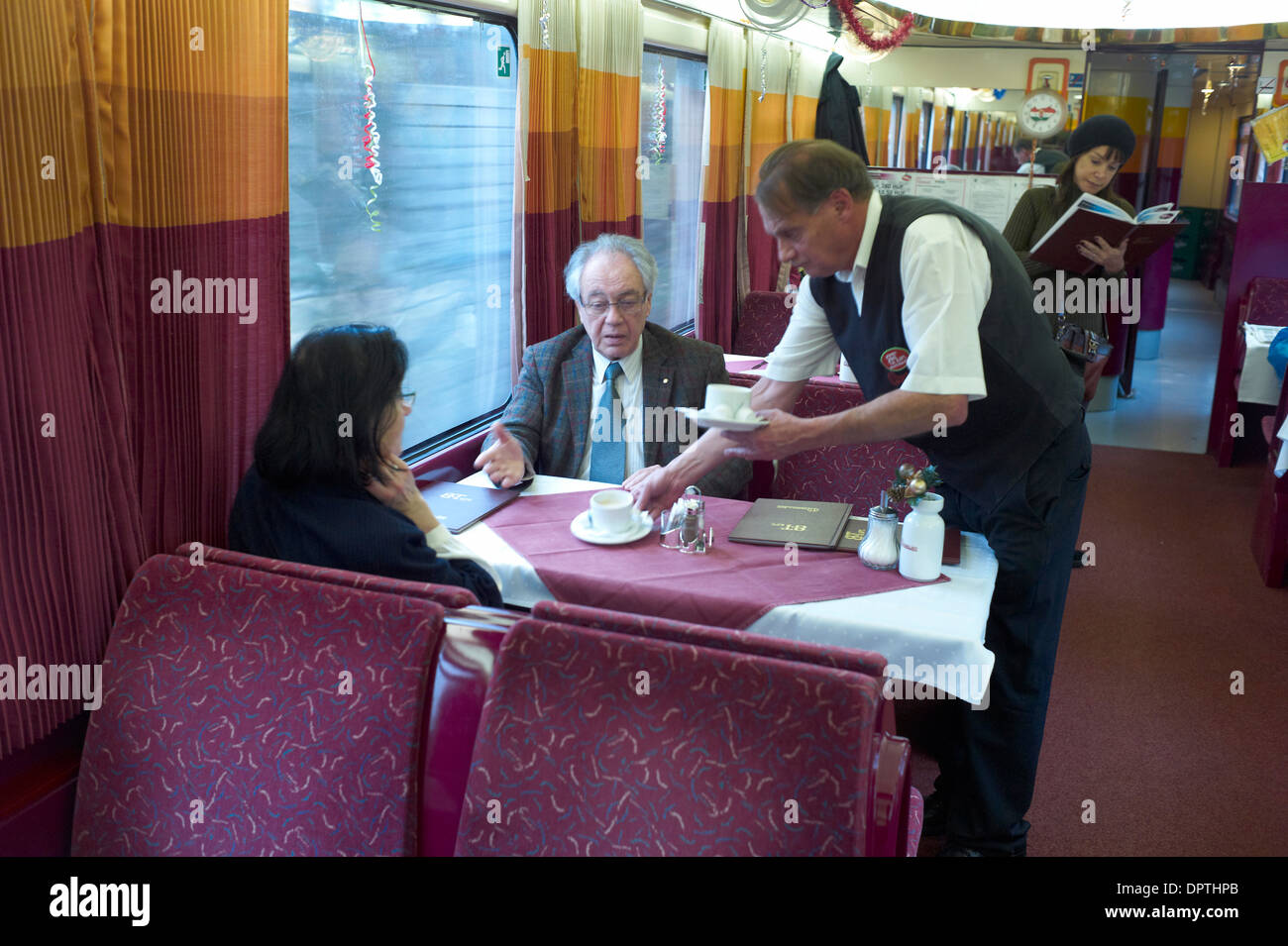 Couple in a Train Restaurant car in Czech Republic between prague and Bratislava being served by a waiter. Stock Photo
