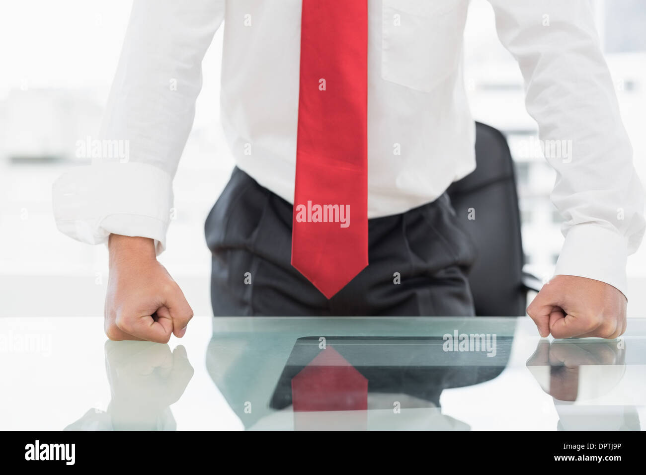 Mid section of a businessman with clenched fists on desk Stock Photo