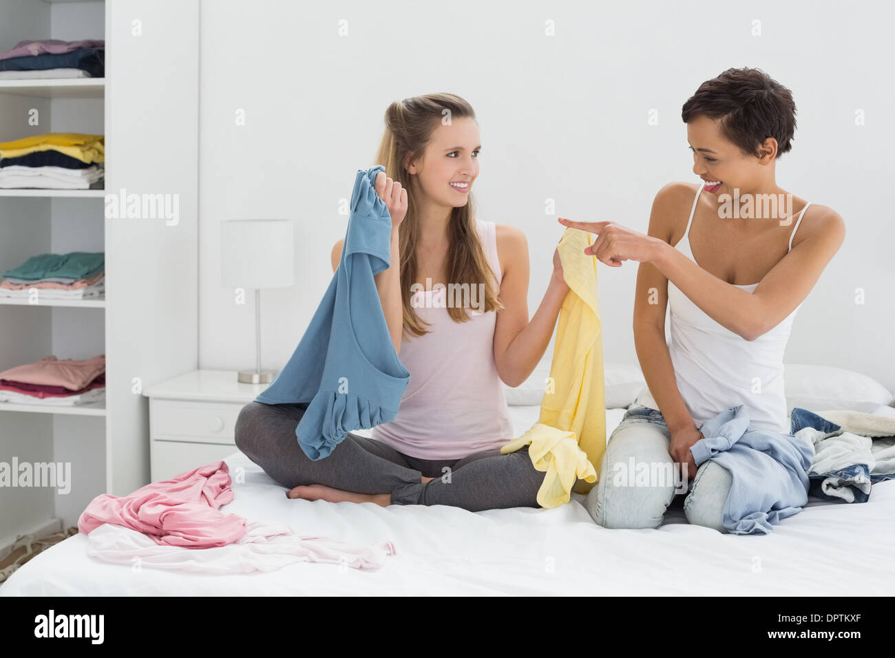 Pretty female friends selecting clothes in bed Stock Photo Alamy