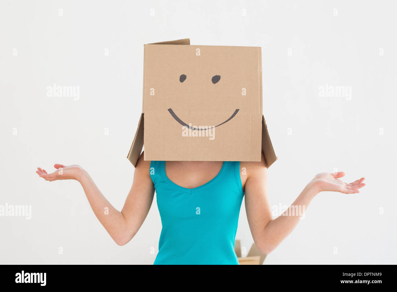 Woman in blue tank top with smiley cardboard box over face Stock Photo