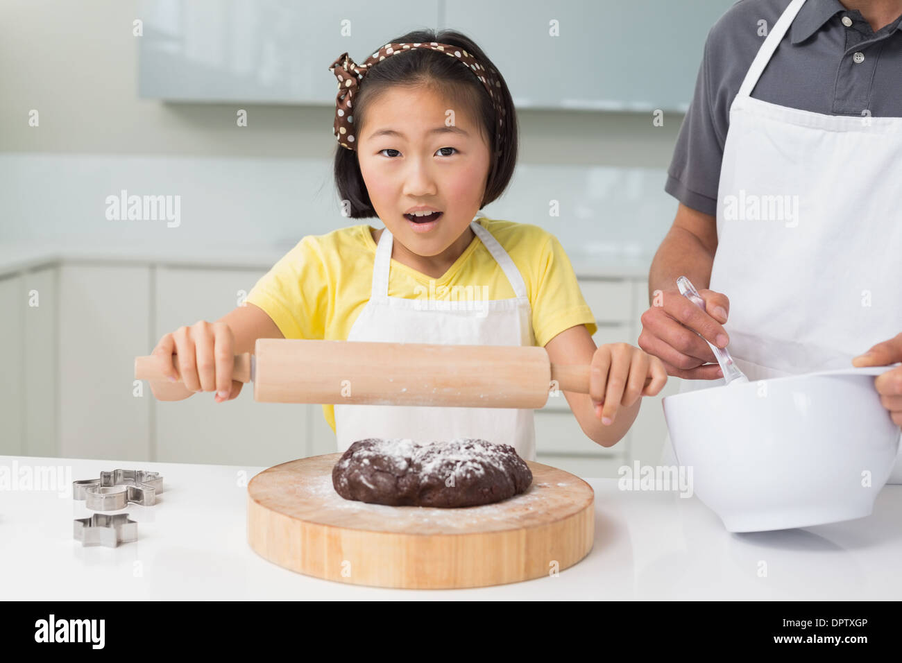 Shocked girl with her father preparing cookies in kitchen Stock Photo
