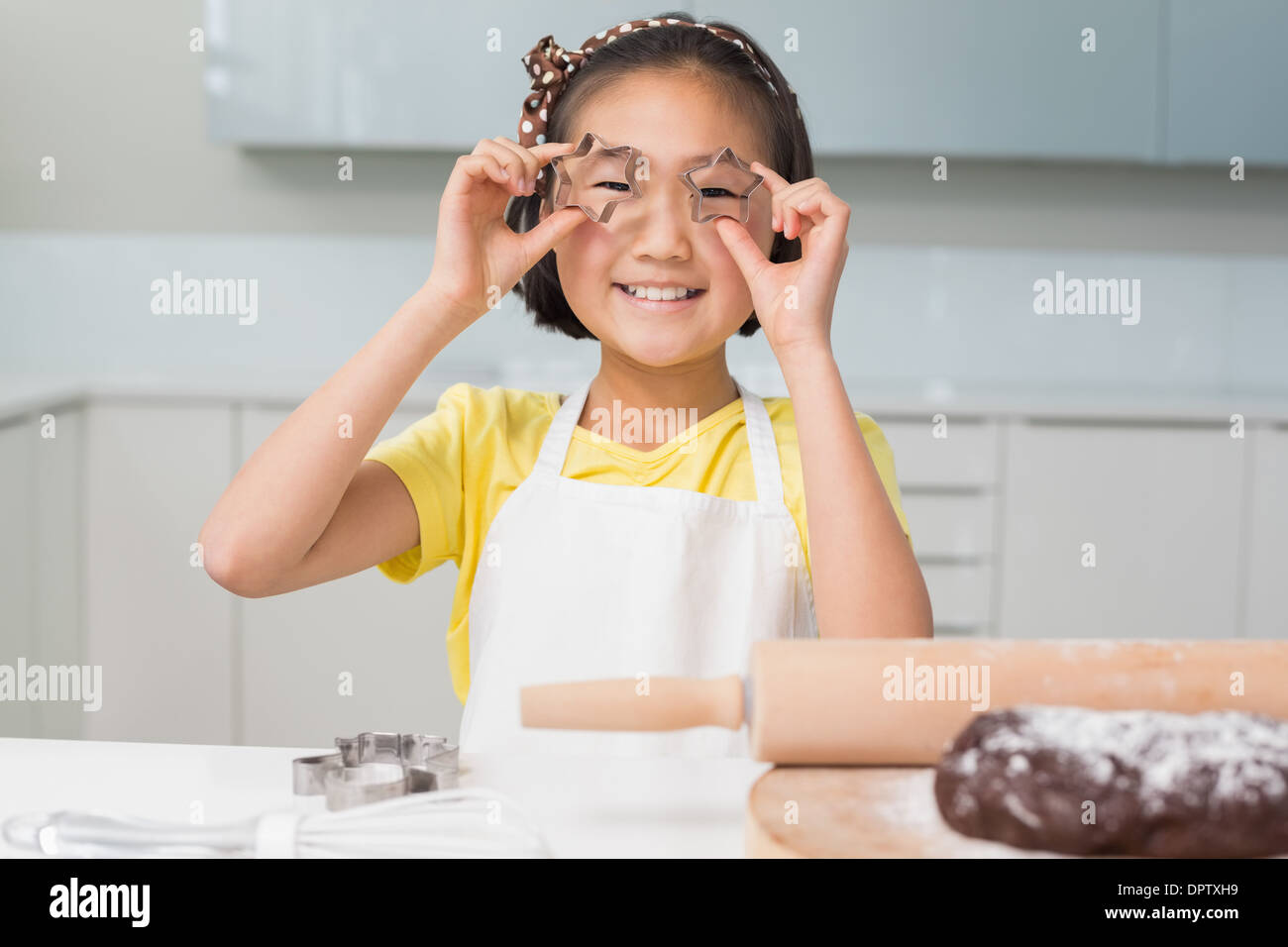 Smiling young girl holding cookie molds in kitchen Stock Photo