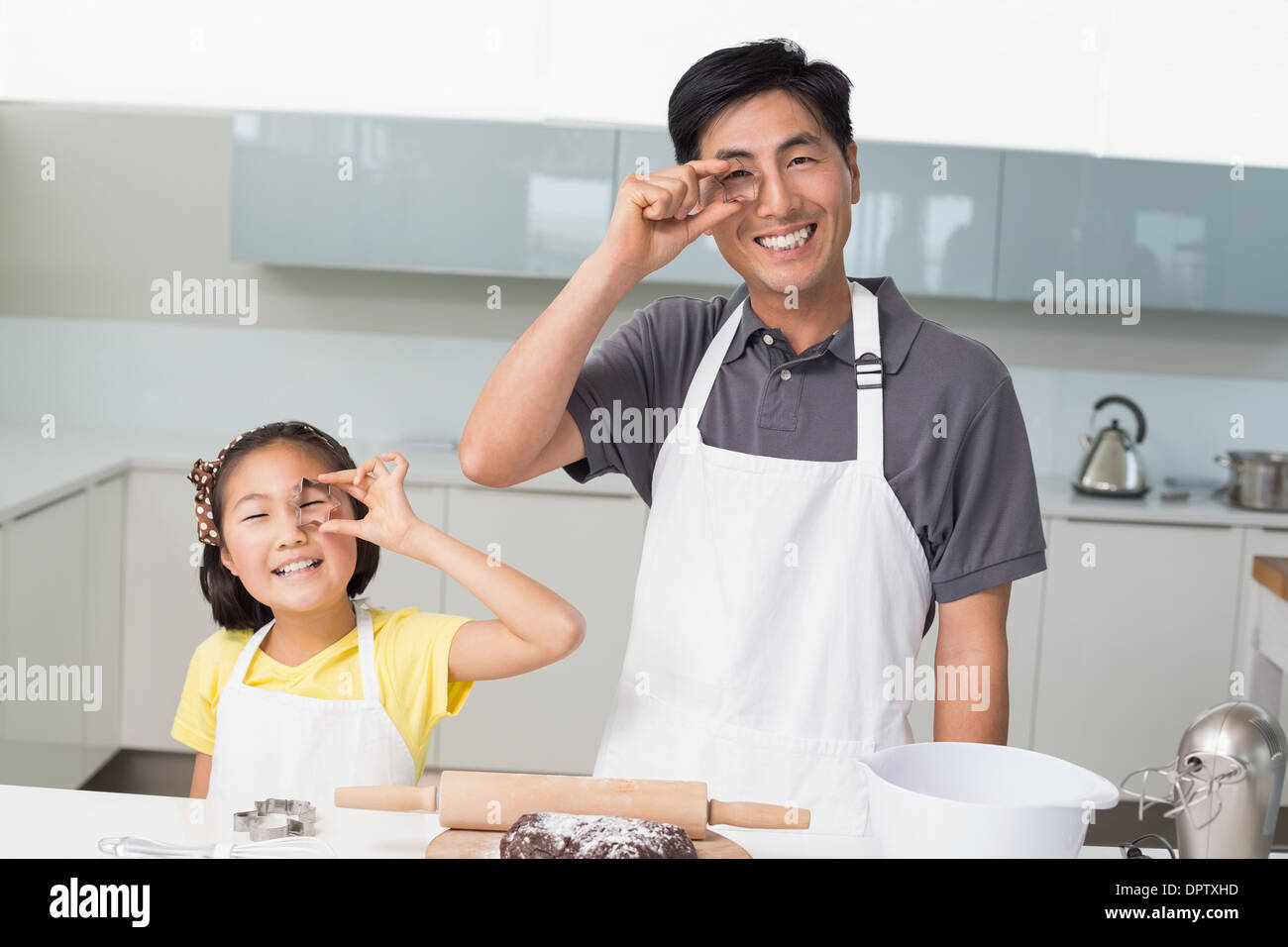 Happy girl with her father holding cookie molds in kitchen Stock Photo