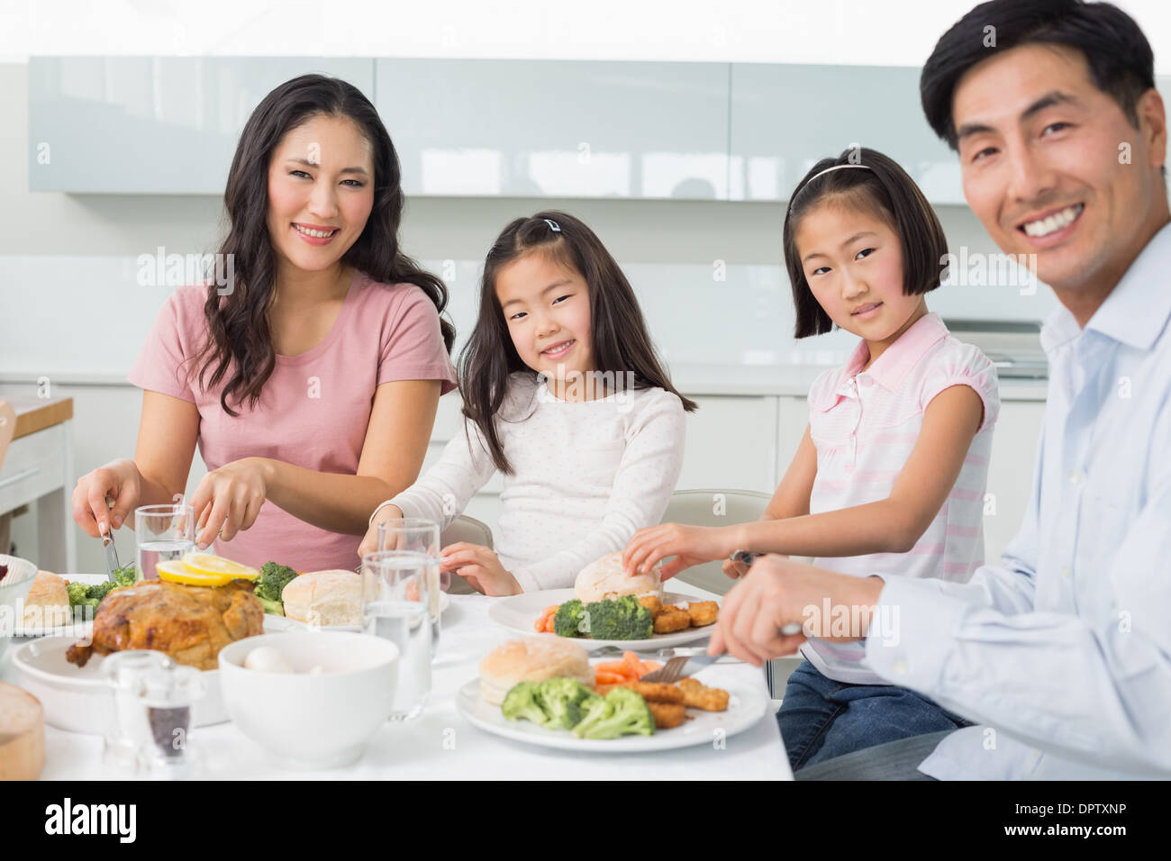 Happy family of four enjoying healthy meal in kitchen Stock Photo - Alamy