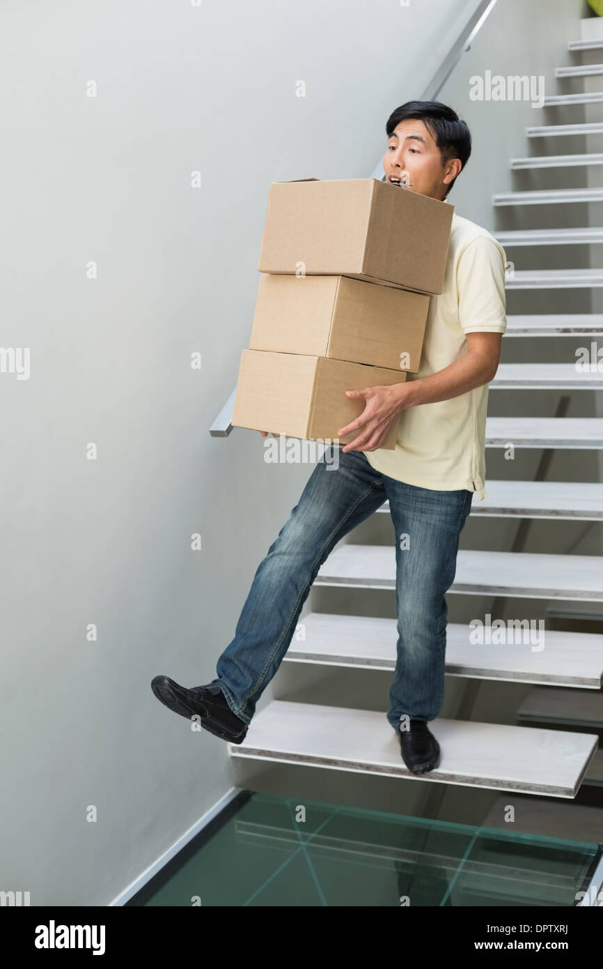 Young man carrying boxes against staircase Stock Photo Alamy