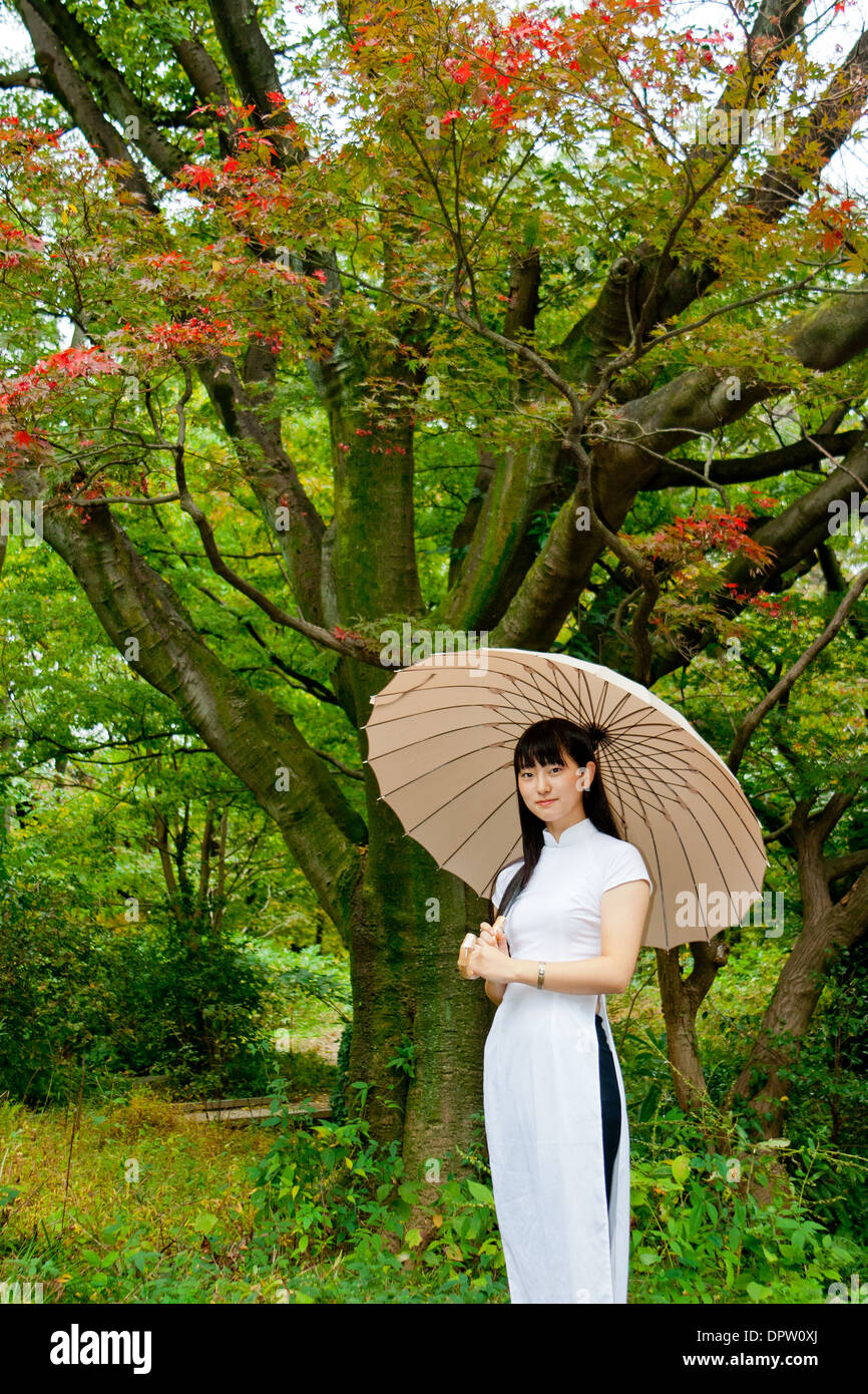 Young Woman Holding Umbrella Under Autumn Trees Stock Photo