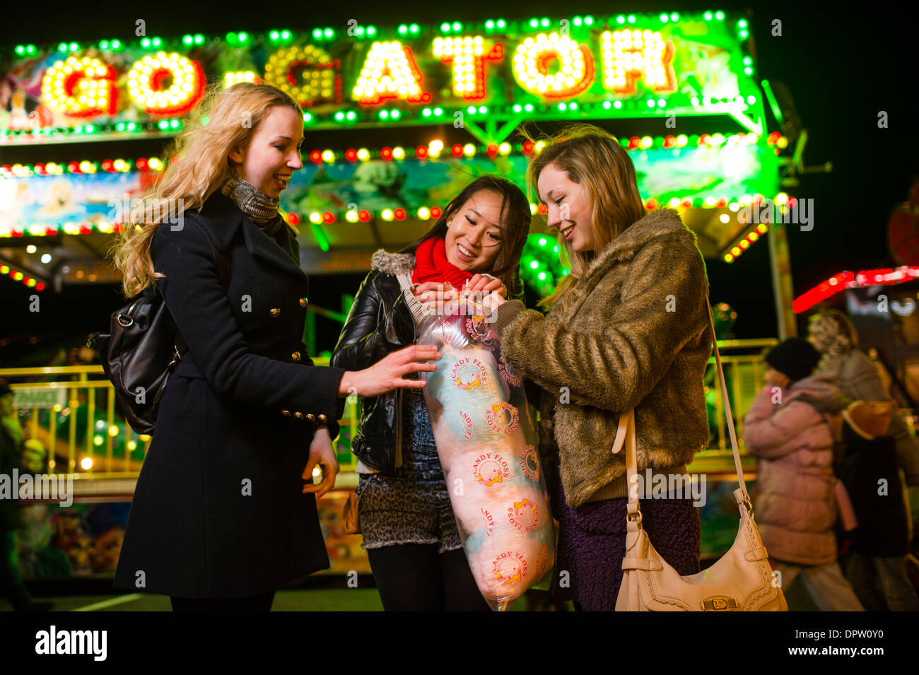 Three Teenage girls friends young women having fun eating candyfloss, at the Aberystwyth November fair Stock Photo