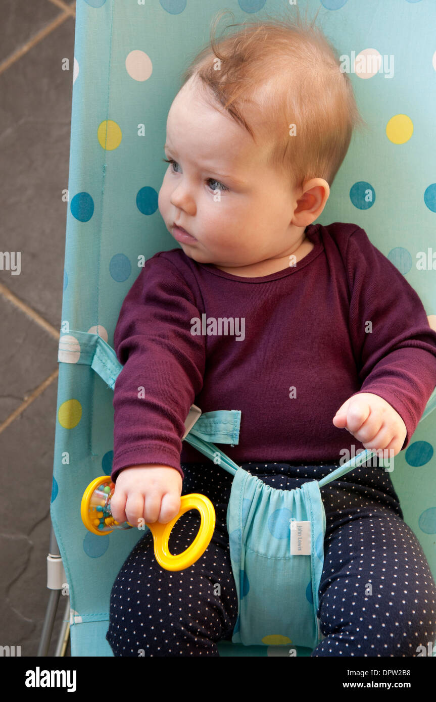 Little baby girl in a baby bouncer looking thoughtful Stock Photo Alamy