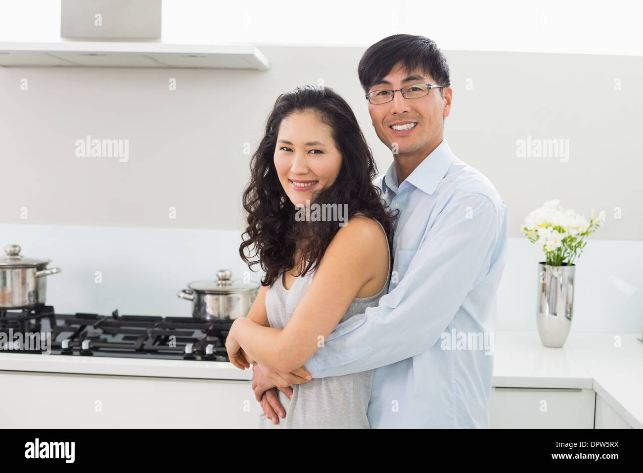 Young man embracing woman from behind in kitchen Stock Photo - Alamy