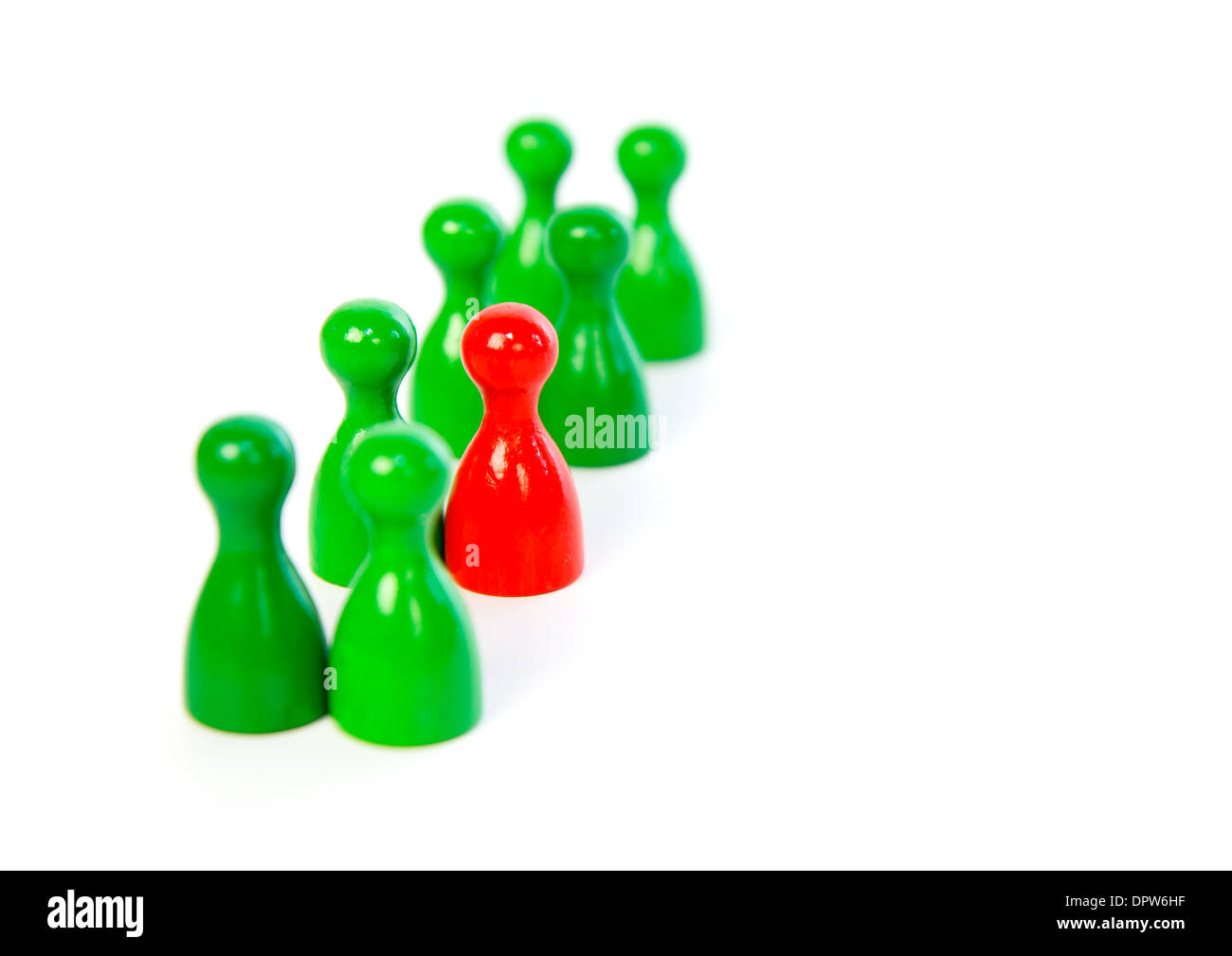 Red pawn in a line-up of green pawns against white background Stock Photo