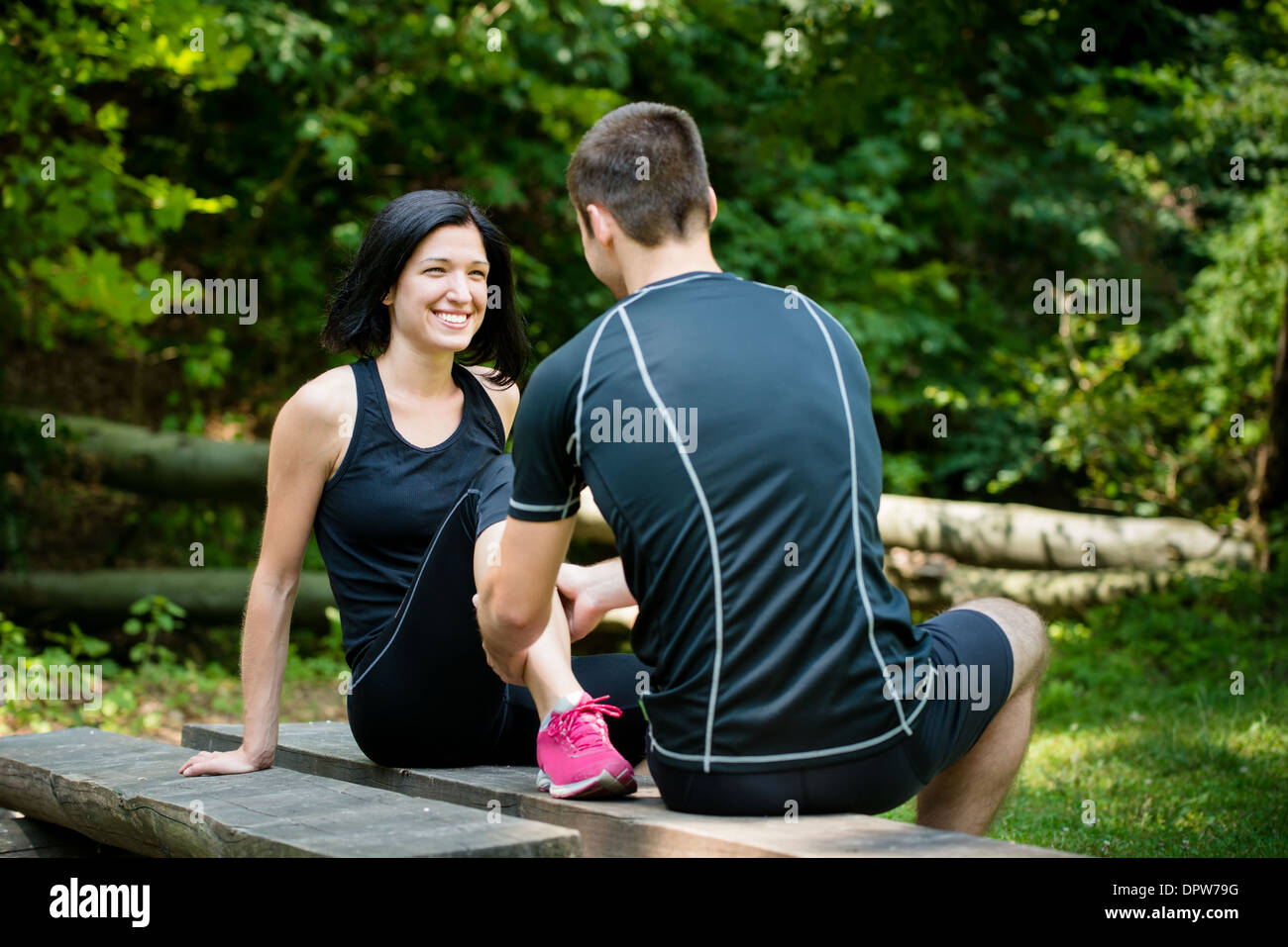 Young man gives massage of calf to smiling woman after jogging Stock Photo