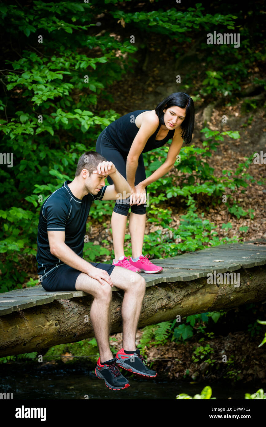 Sport couple relaxing after jogging in nature (foot bridge in forest) Stock Photo