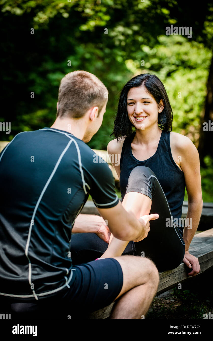 Young man gives massage of calf to his friend after sport training Stock Photo