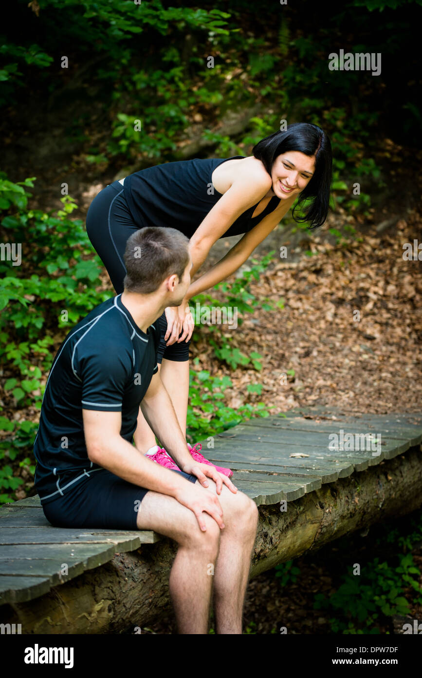 Sport couple relaxing after jogging on foot bridge in forest Stock Photo