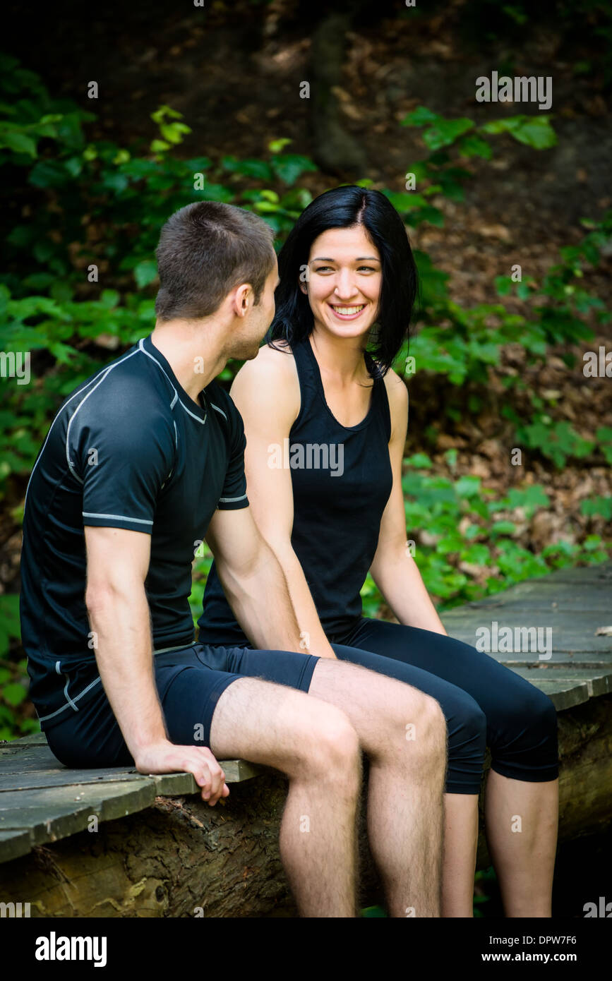 Young sport couple relaxing after sport training on foot bridge in nature Stock Photo
