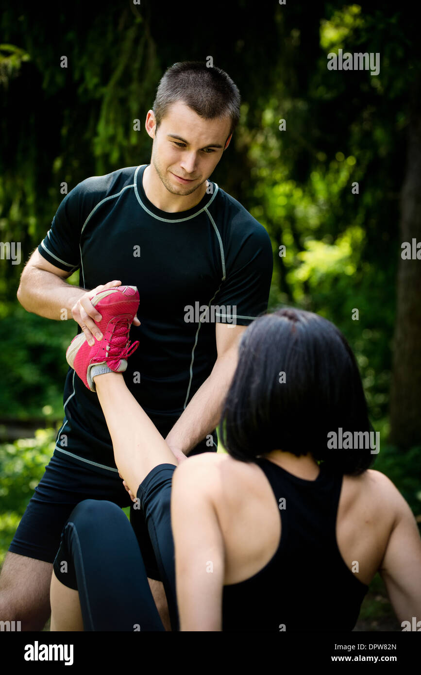 Man helps woman with muscle spasm - stretching her leg Stock Photo
