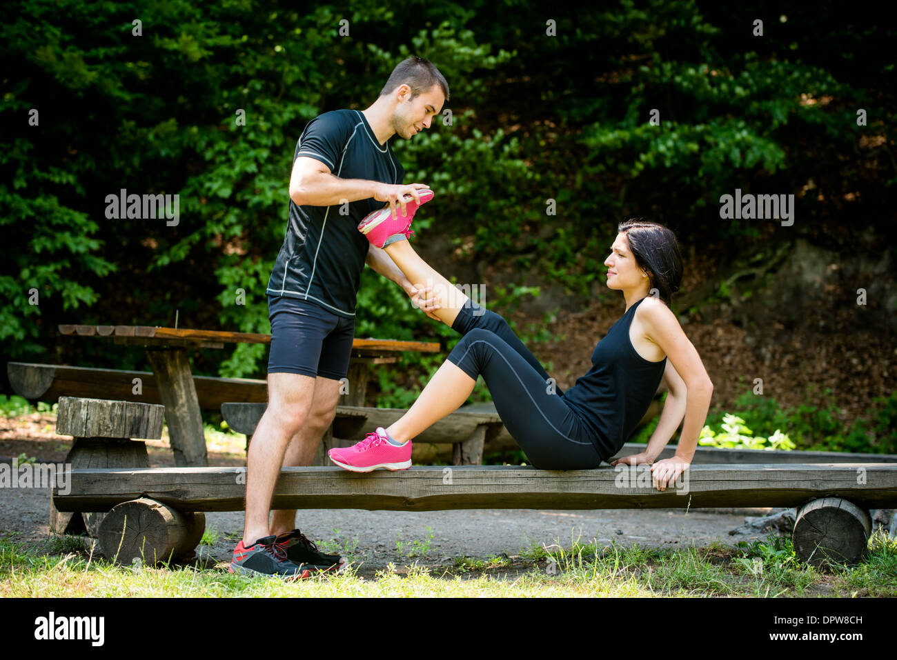 Man stretches womans leg - muscle spasm after sport training Stock Photo