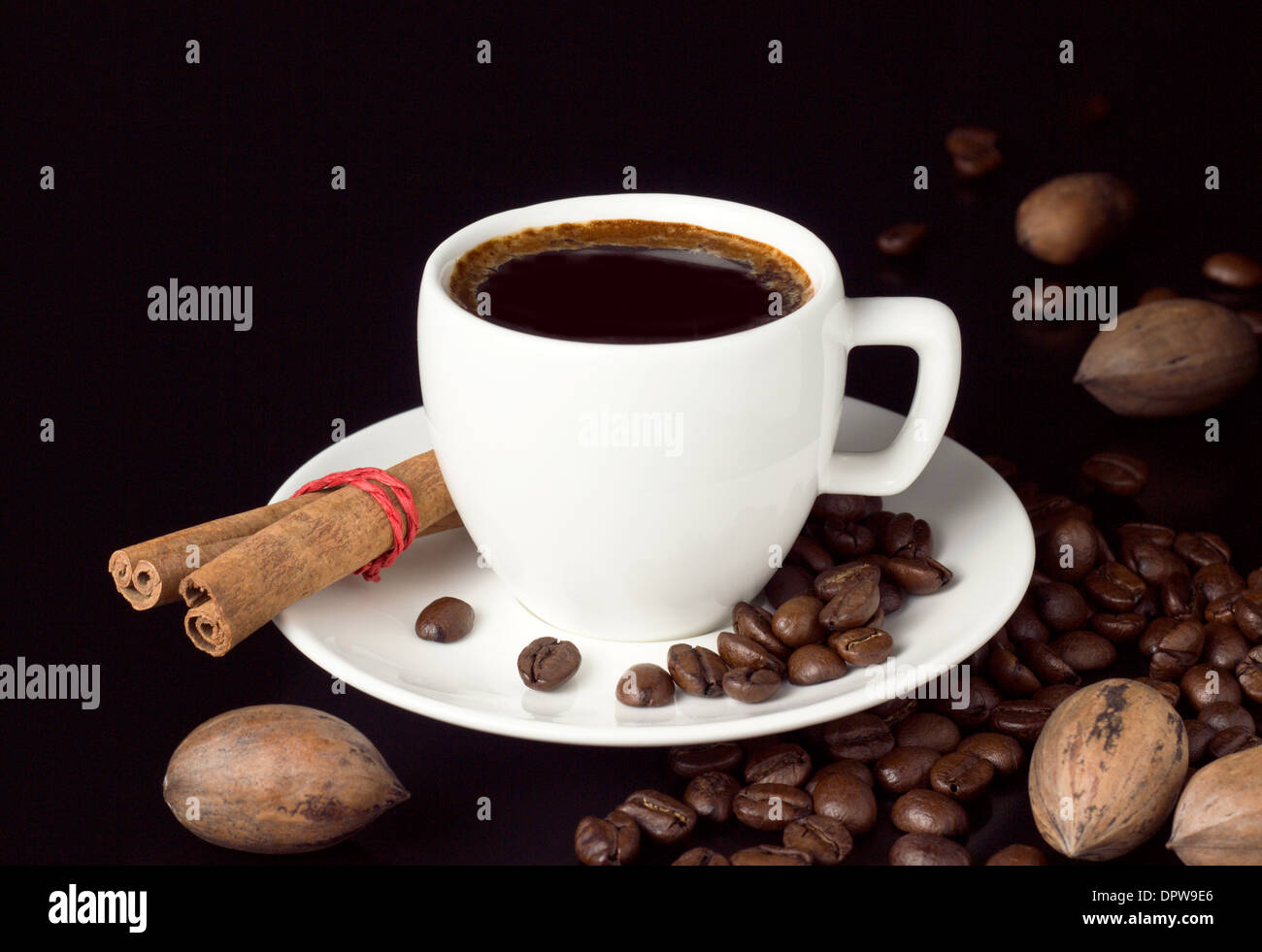 coffee cup with roasted beans and nuts on black table Stock Photo