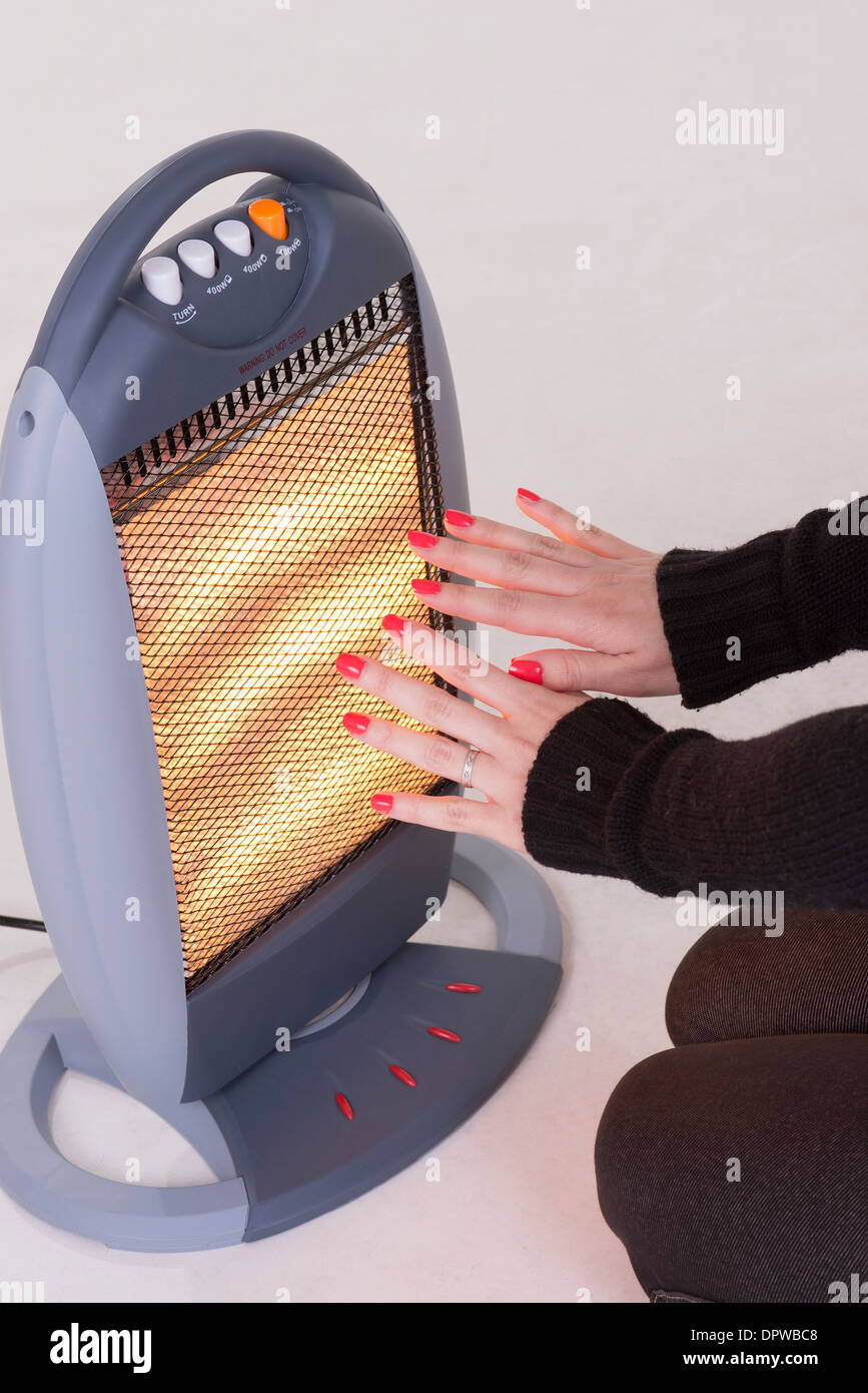 Woman warming hands on an electric fire Stock Photo