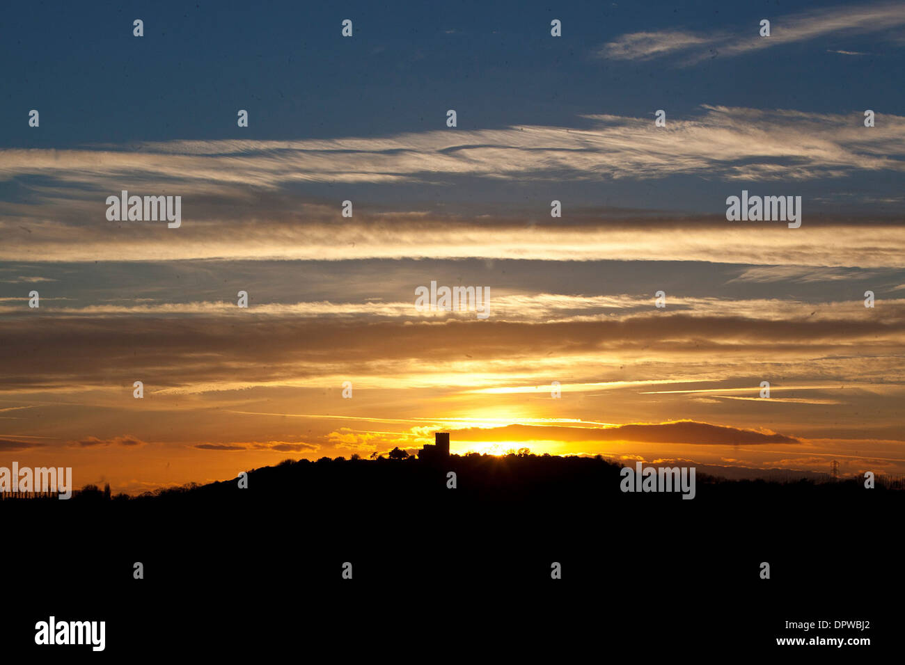 The sun sets behind the Church of St Mary and St Hardulph in Breedon on the Hill, Leicestershire Stock Photo