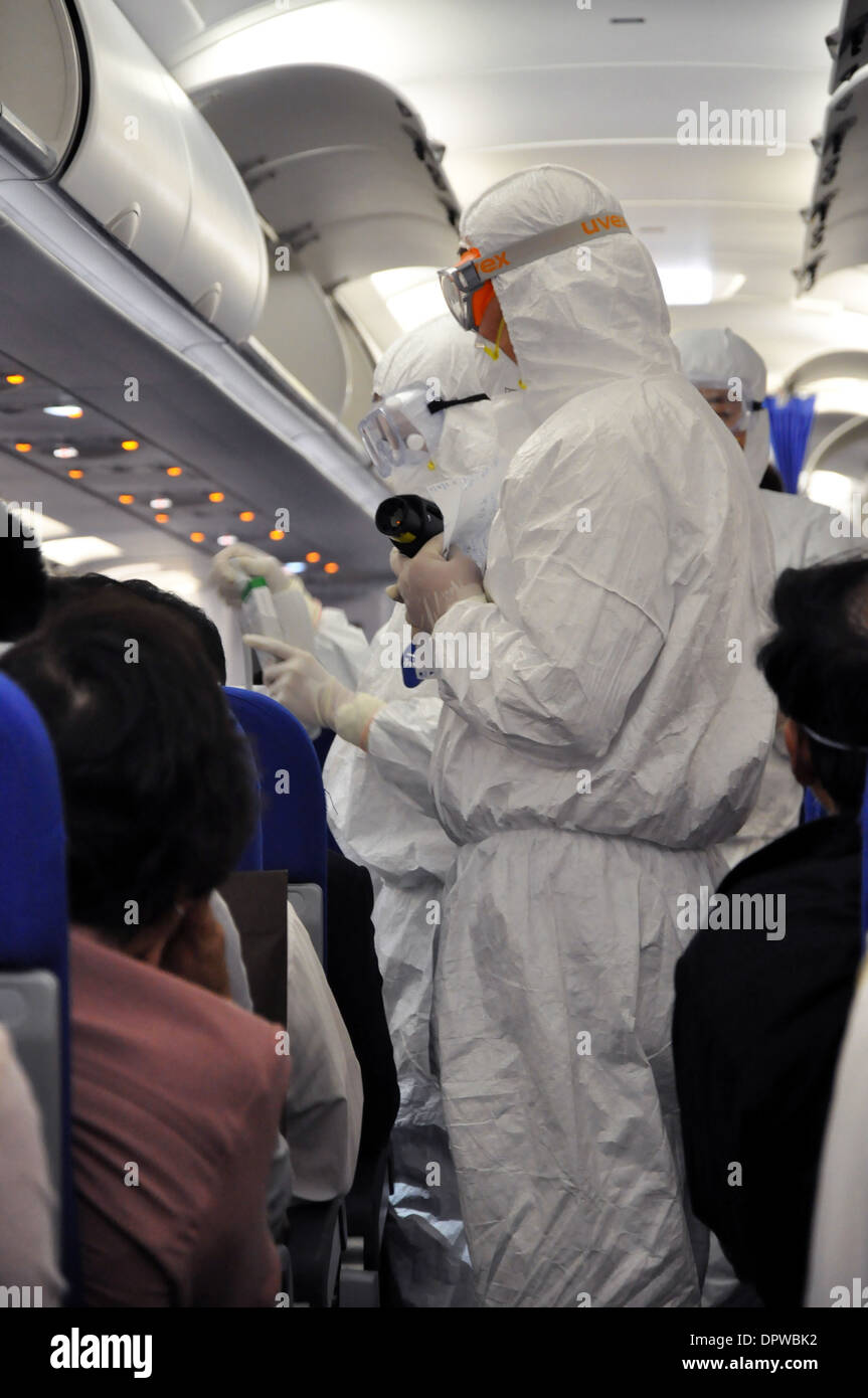 Men in white protection suits checking airplane passengers for fever and H1N1 flu symptoms before arrival in Shanghai China Stock Photo