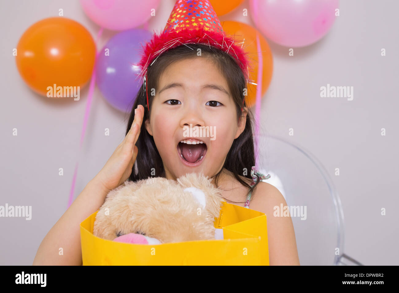 Shocked little girl with gift at her birthday party Stock Photo