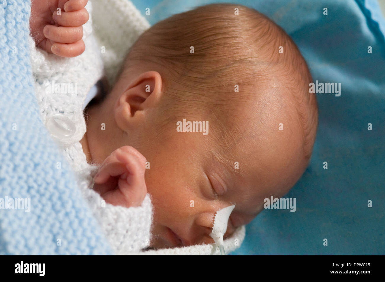Premature newborn baby boy in hospital cot with a feeding tube attached to his nose Stock Photo
