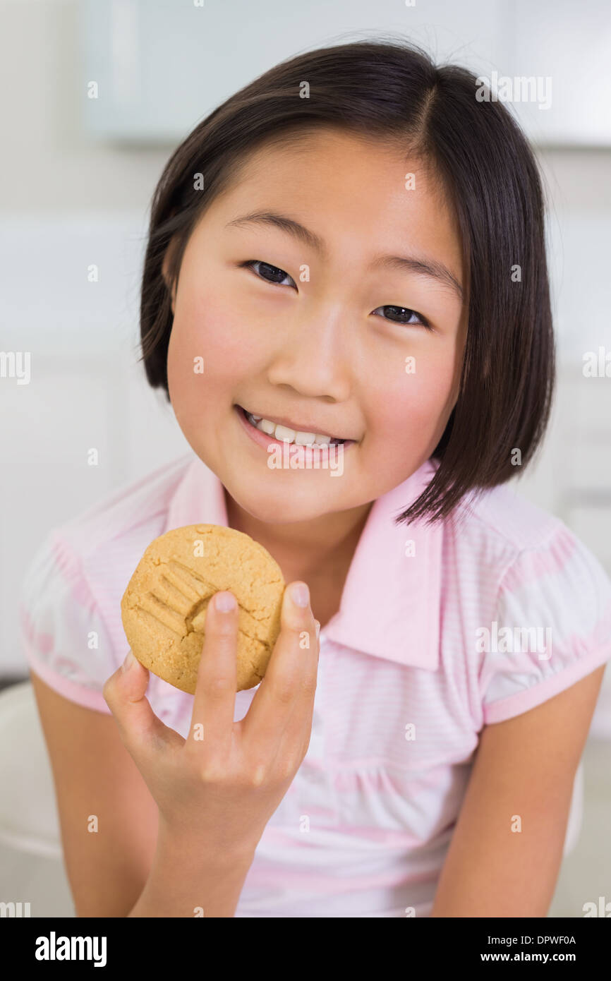 Portrait of a smiling young girl enjoying cookie Stock Photo - Alamy