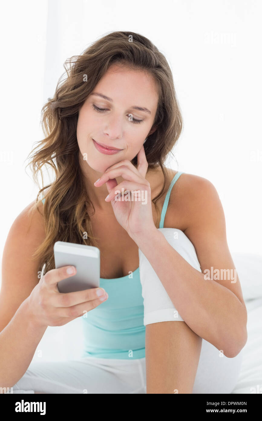 Smiling woman looking at mobile phone in bed Stock Photo
