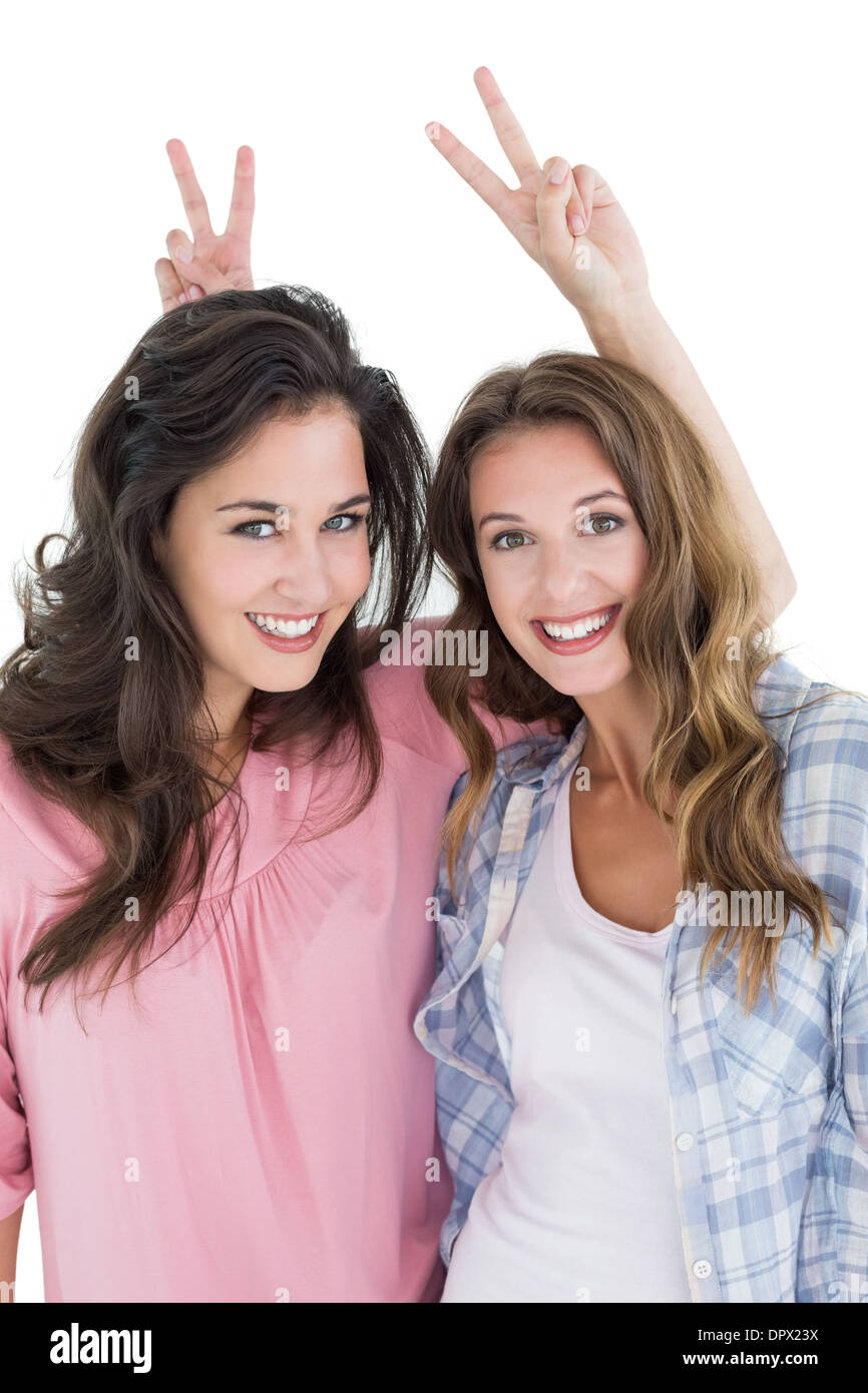 Female friends gesturing peace sign over heads Stock Photo