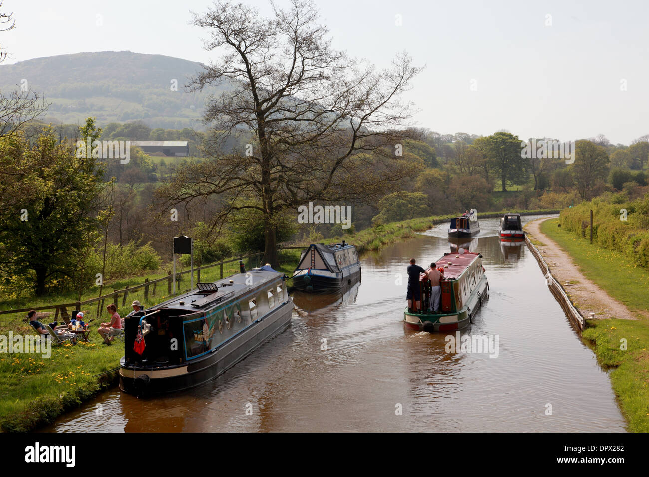 Narrowboats at the bottom of the Bosley flight of locks on the Macclesfield Canal with the hill, “the Cloud”, in the background Stock Photo