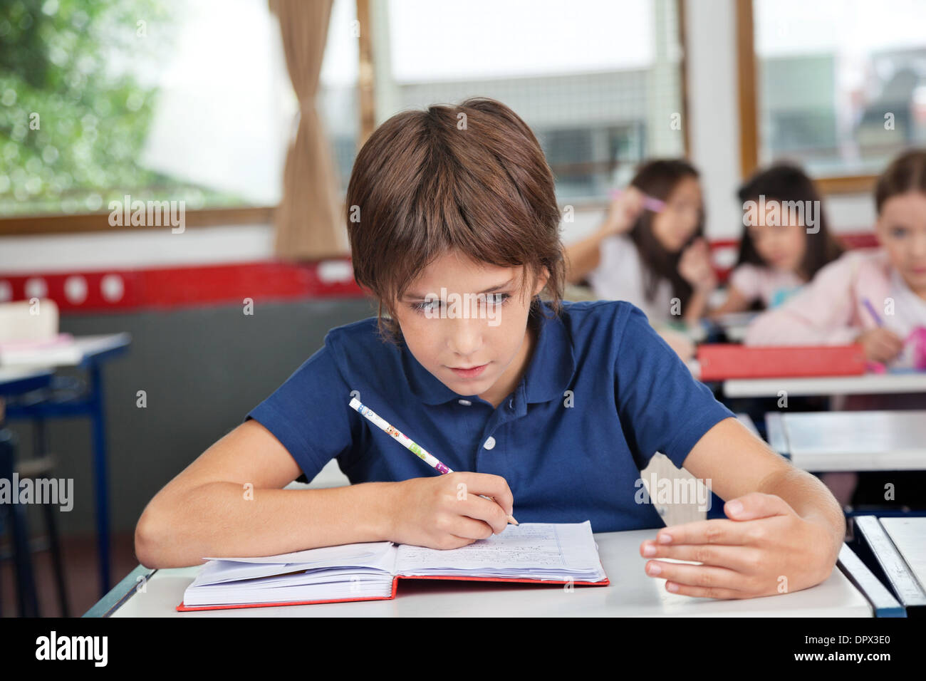 Schoolboy Cheating At Desk During Examination Stock Photo