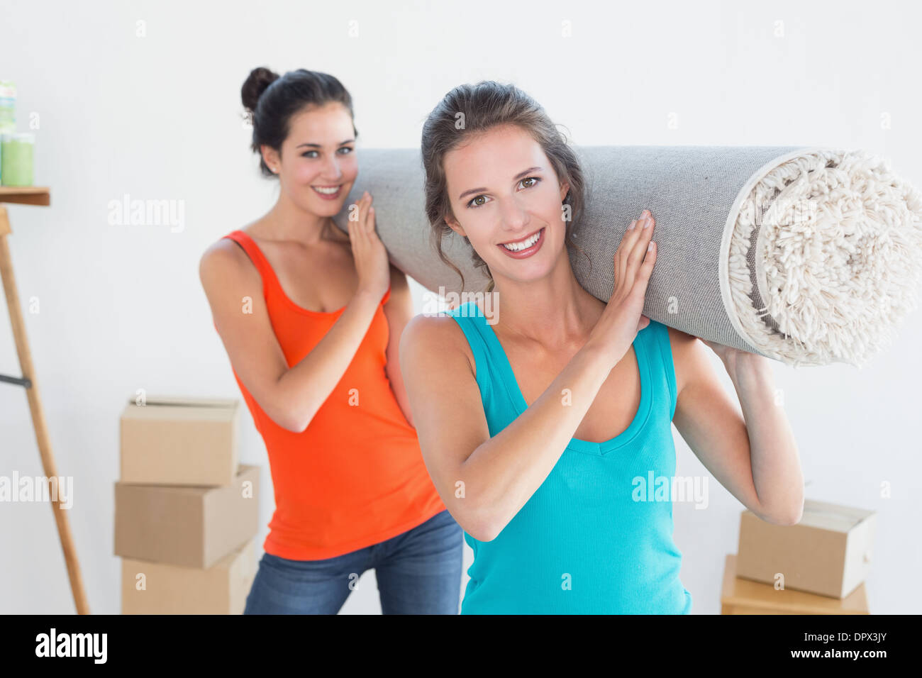 Friends carrying rolled rug after moving in a house Stock Photo - Alamy