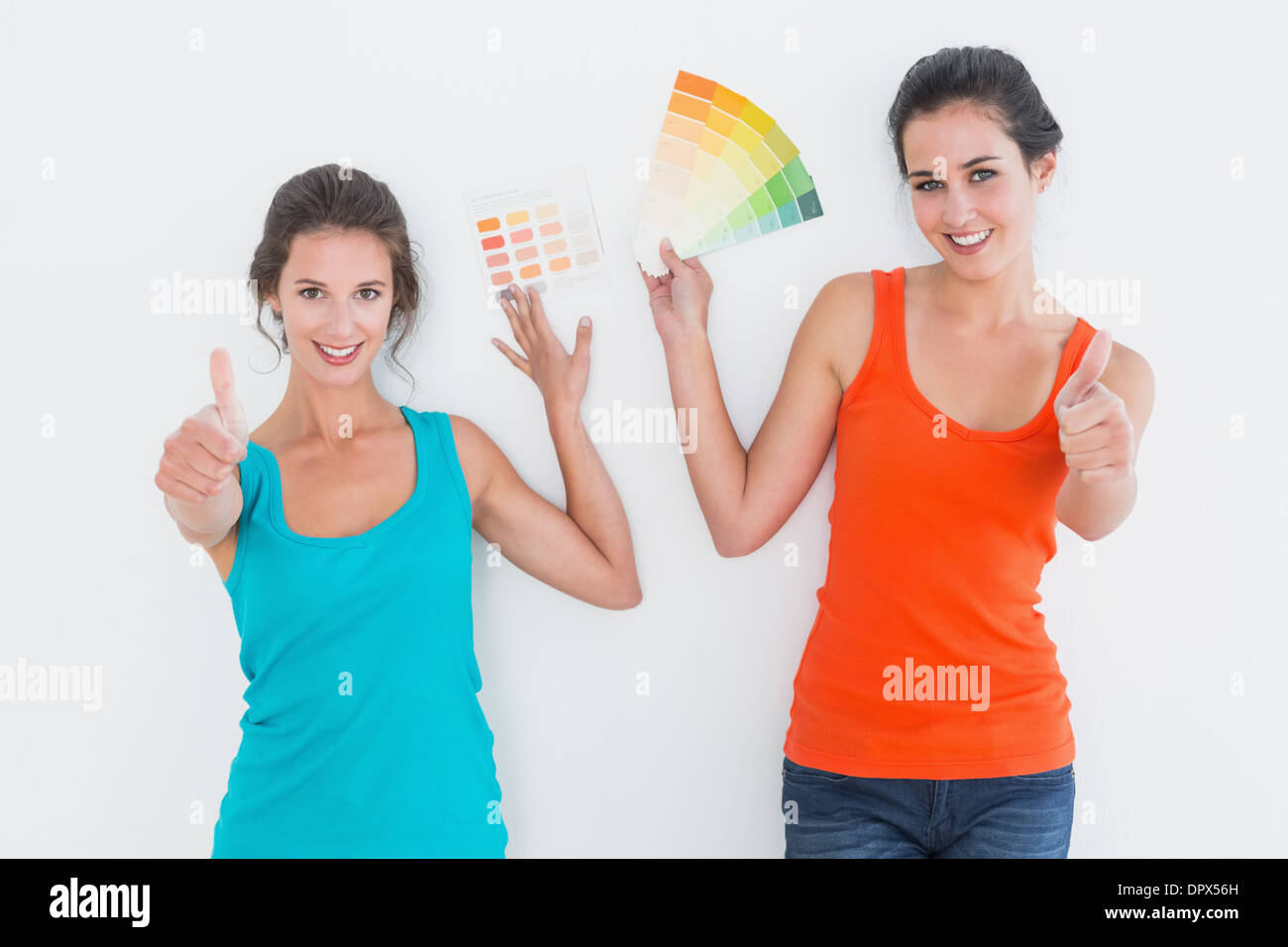 Female friends with color swatches gesturing thumbs up Stock Photo
