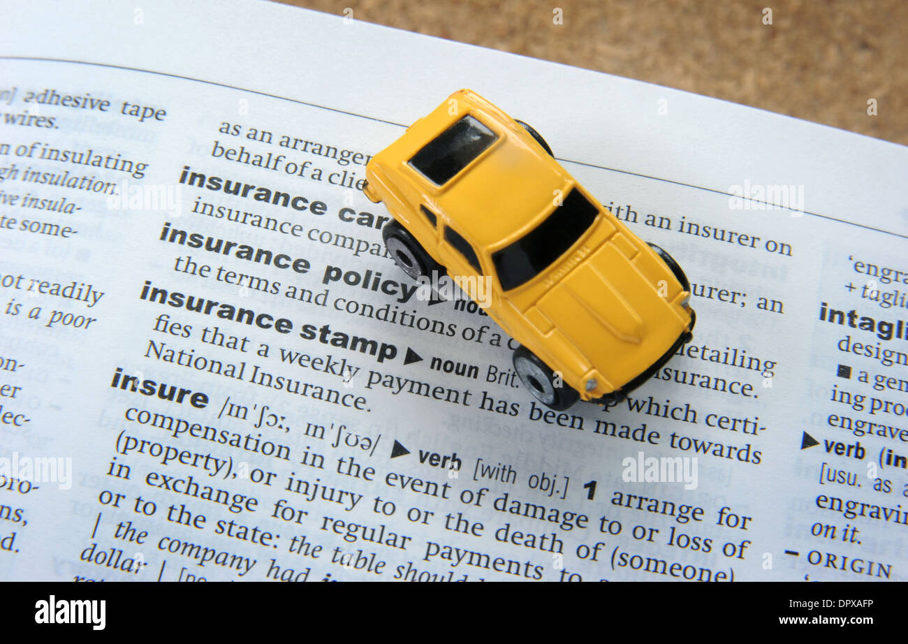 TOY CAR WITH DICTIONARY WITH INSURANCE WORD RE CAR INSURANCE POLICY POLICIES SCHEME RISING PRICES COSTS ACCIDENT DAMAGE PRICES Stock Photo