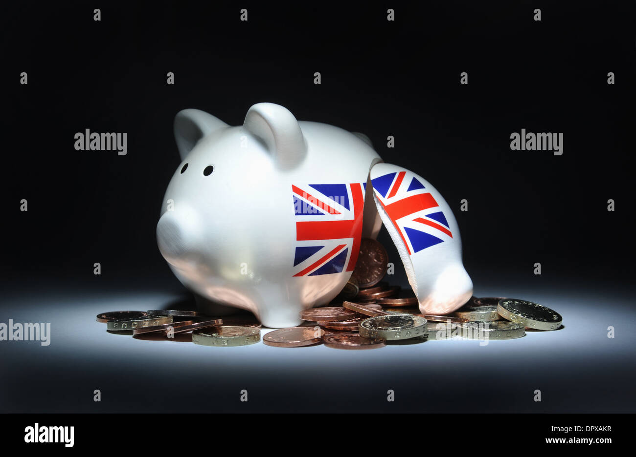 BROKEN BRITISH PIGGY BANK SPILLING COINS RE THE ECONOMY UNION JACK SAVINGS INCOMES WAGES INFLATION HOUSEHOLD BUDGETS MONEY POUND Stock Photo