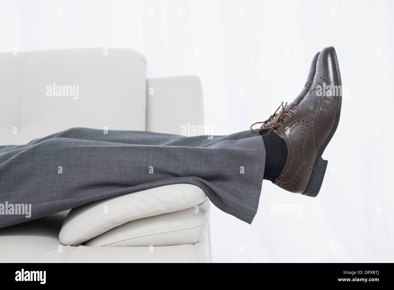 Low section side view of a businessman resting on sofa Stock Photo