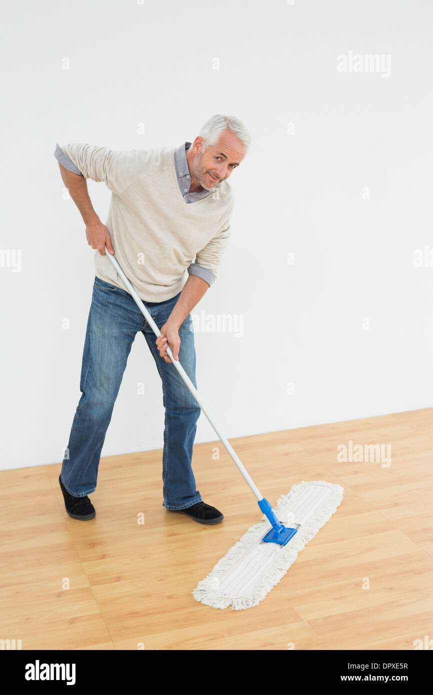 Full length portrait of a smiling mature man mopping the floor Stock Photo