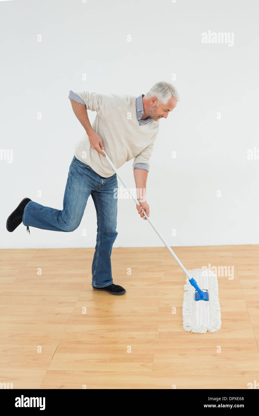 Full length side view of a mature man mopping the floor Stock Photo