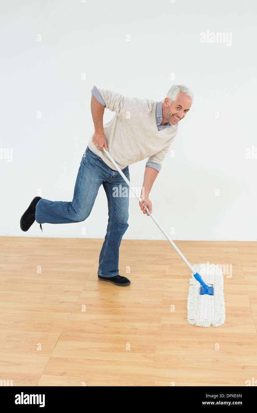 Portrait of a cheerful mature man mopping the floor Stock Photo