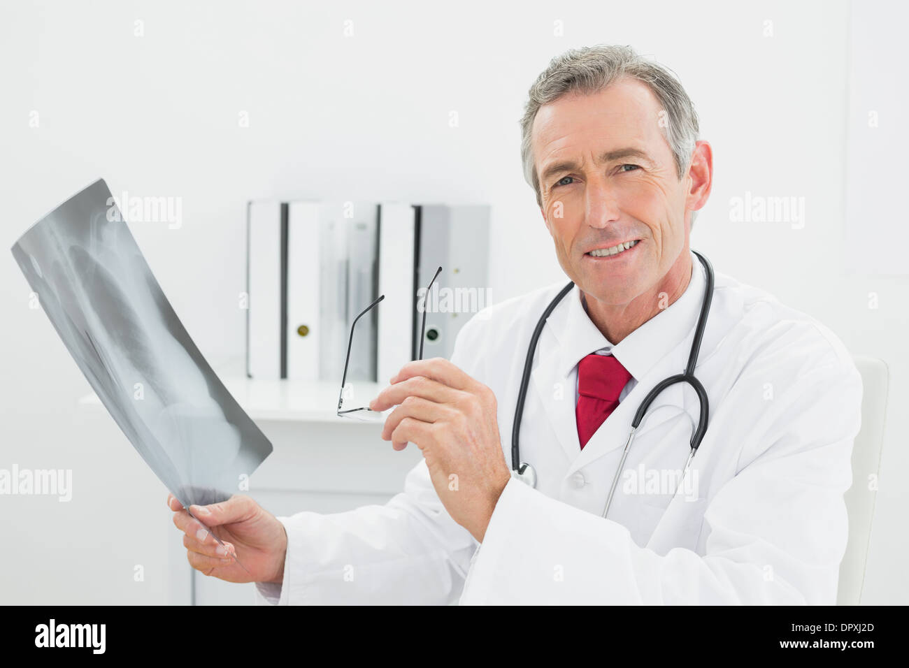 Confident doctor with x-ray picture of lungs in office Stock Photo
